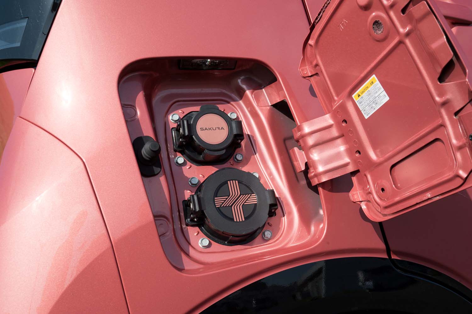 充電ポートは車体の右側後部に用意される。上の普通充電用には「SAKURA」ロゴが、下の急速充電用には水引模様があしらわれる。