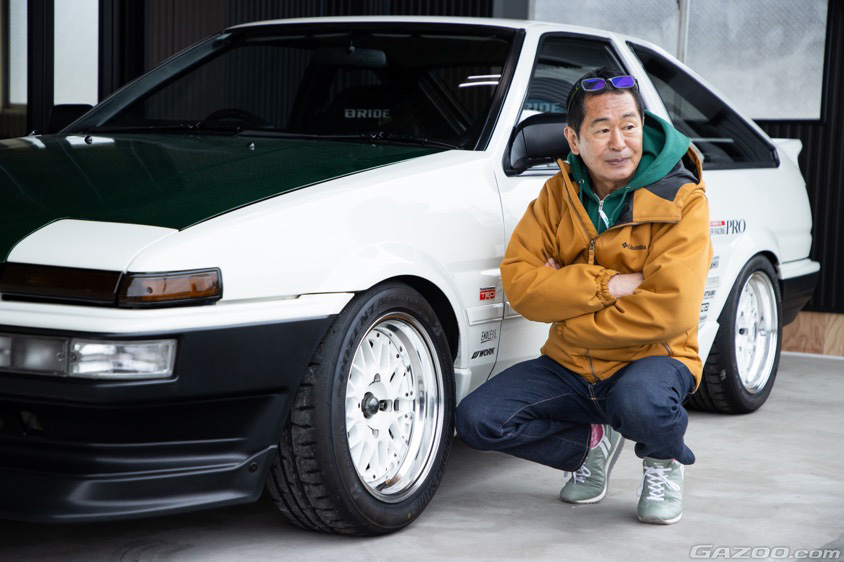 愛車のスプリンタートレノ「スーパーマメ号」の前に座る土屋圭市氏