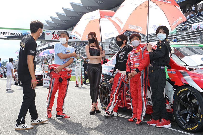 長村さんは、クルマのメンテナンスからレース中のサインガードでの仕事から、ご覧の通りドライバーへの傘さしまでなんでもこなします。