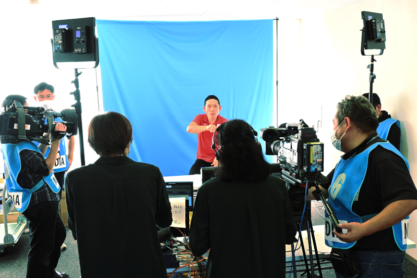 リアルタイム手話実況を担当した早瀨憲太郎さんにカメラの手前から手話で実況を伝える