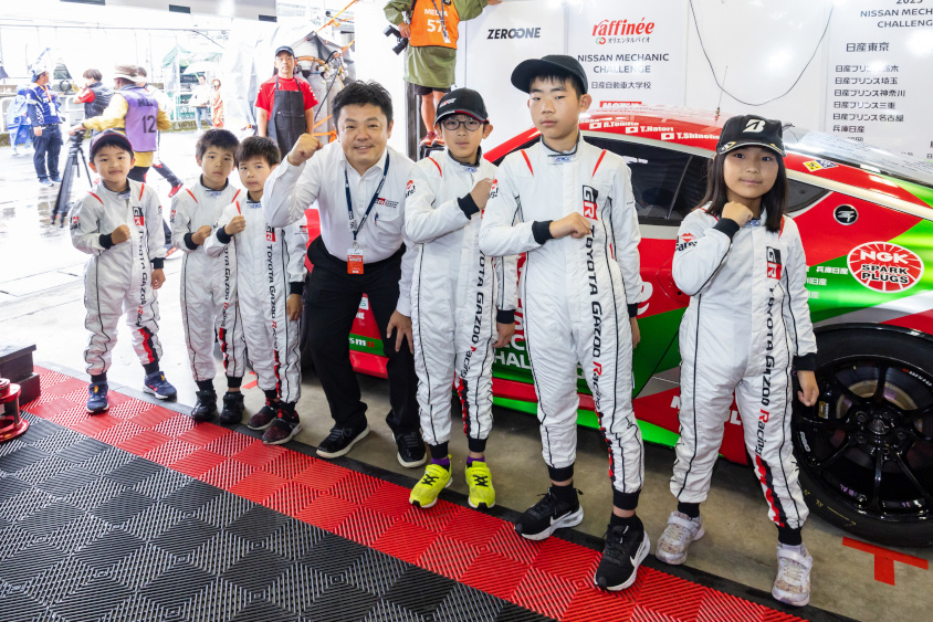 GRのレーシングスーツを着た子供達と記念撮影をするGRの高橋智也プレジデント
