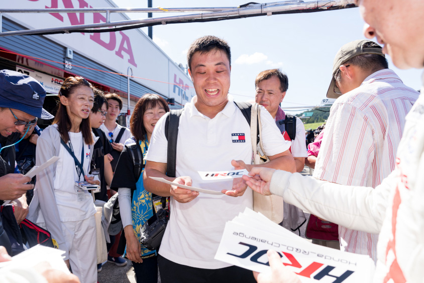 笑顔でステッカーを受け取るピットツアー参加者