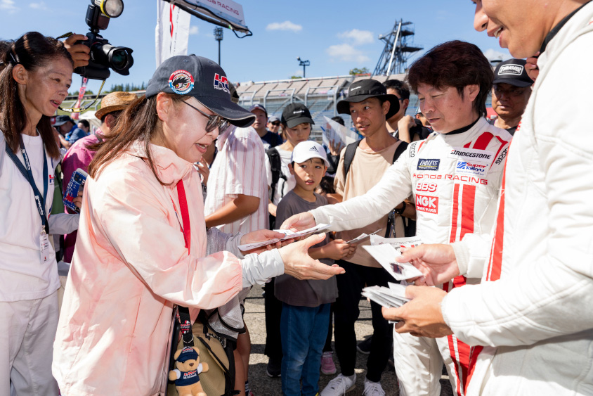 柿沼秀樹選手からステッカーをもらうピットツアー参加者