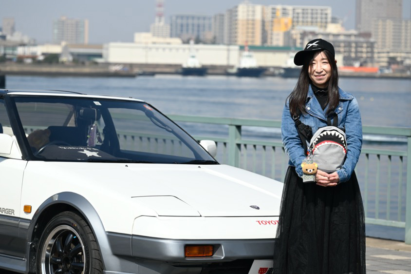 トヨタ・MR2（AW11型）と笑顔で記念撮影するオーナーのあけみこさん