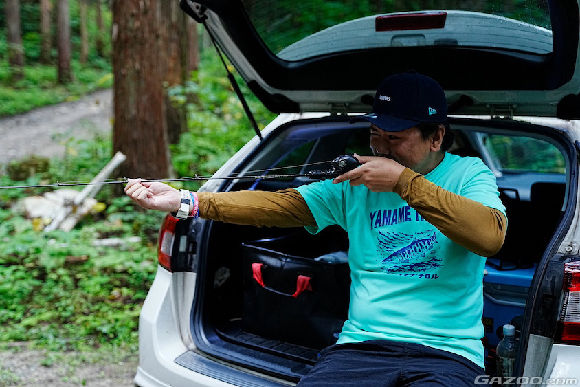 スバル・レヴォーグに座りロッドを調整する恩田直人さん