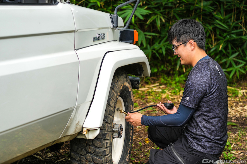 トヨタ・ランドクルーザー70のタイヤ交換をするオーナー