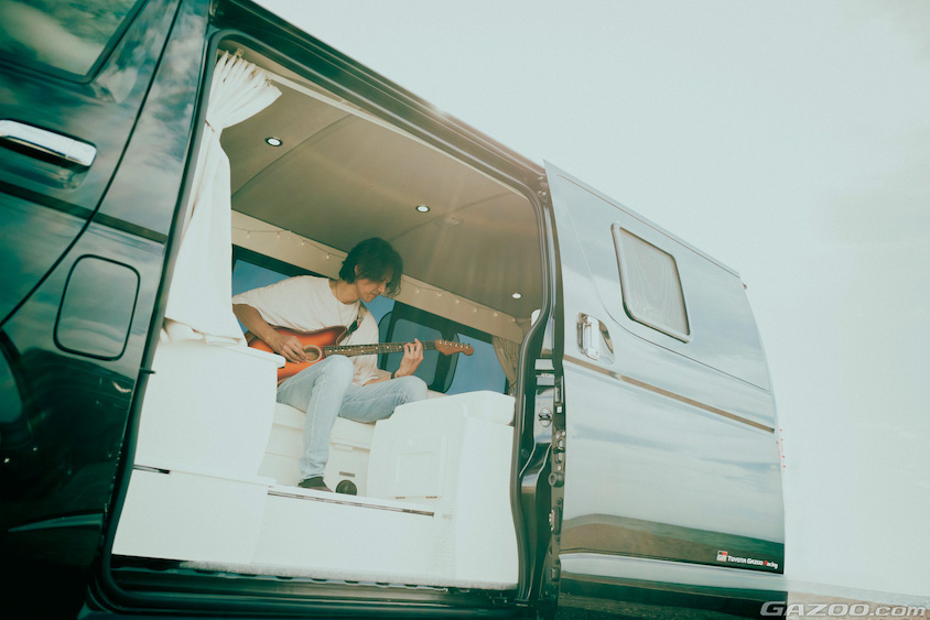 トヨタ・ハイエースの中でギターを弾くオーナーさん