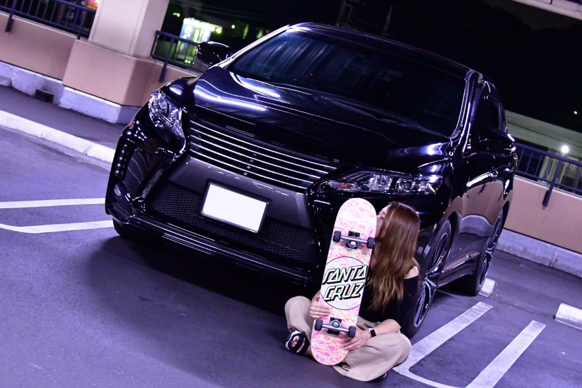 トヨタ・ハリアーの前でボードを持つayakaさん