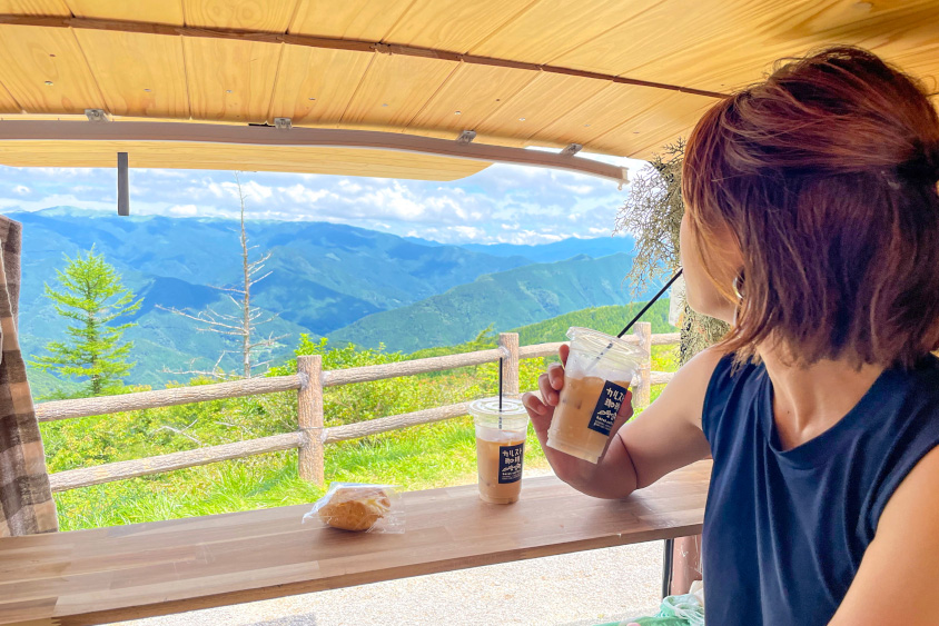 トヨタ・ハイエースでコーヒーを飲みながら外を眺めるあやかさん