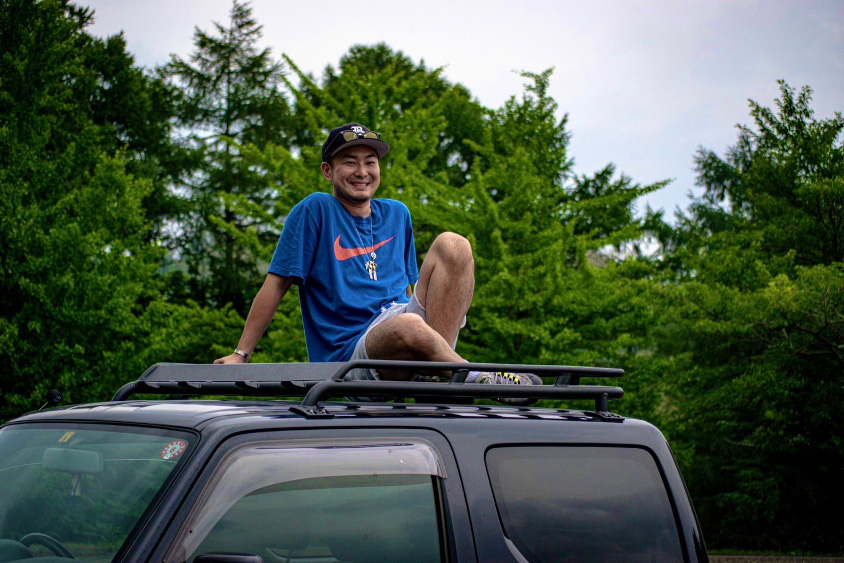 スズキ・ジムニーの屋根に乗るオーナー