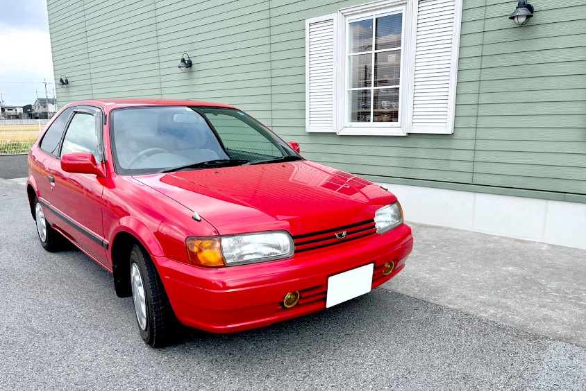 トヨタ・カローラⅡティアラと緑の家の壁