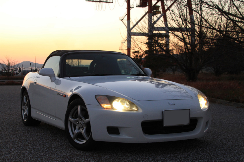 夕暮れの中ヘッドライトが輝くホンダ・S2000