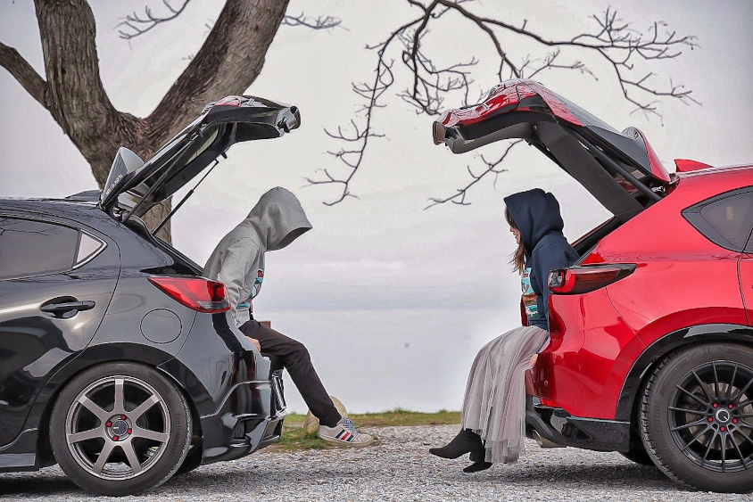 マツダ・デミオとCX-5のラゲッジに腰掛けるチカさんご夫妻