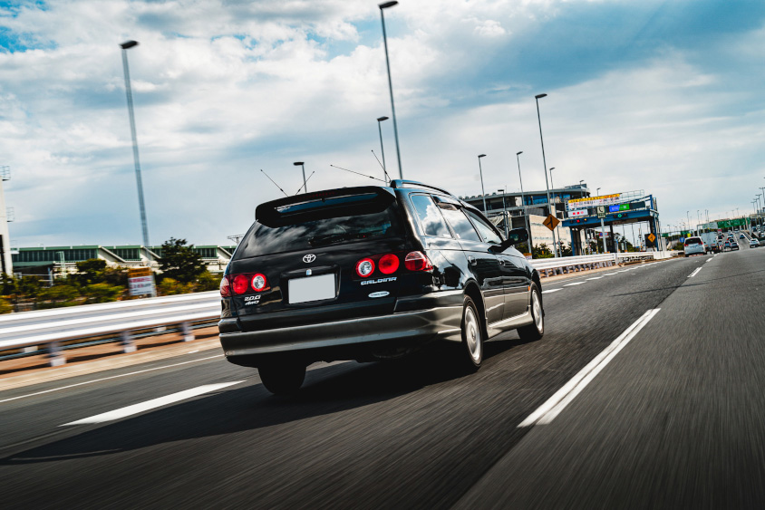 走行するトヨタ・カルディナのリアビュー