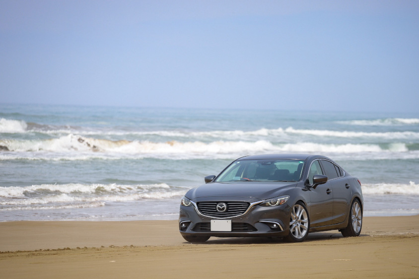 千里浜の海をバックにするマツダ・アテンザ