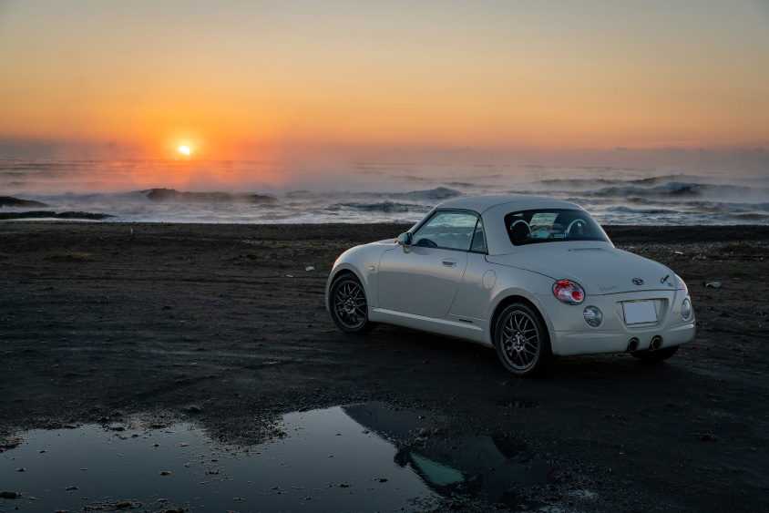 ダイハツ・コペンと海に沈む夕日