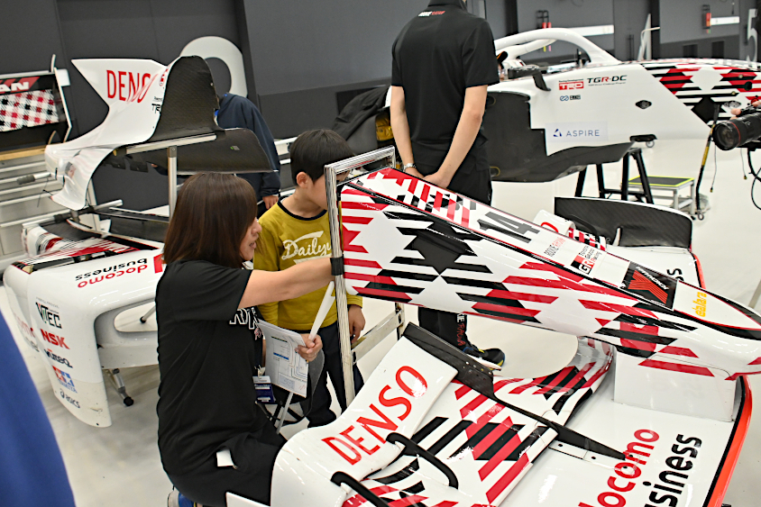 スーパーフォーミュラマシンのノーズコーンをのぞき込むROOKIE Racingキッズガレージツアーの参加者