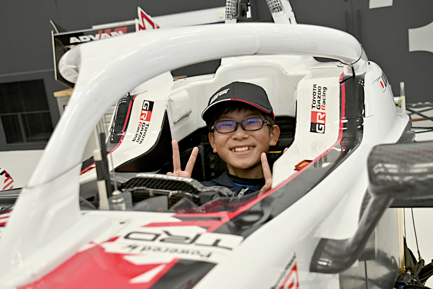 スーパーフォーミュラマシンの運転席で笑顔を見せるROOKIE Racingキッズガレージツアーの参加者