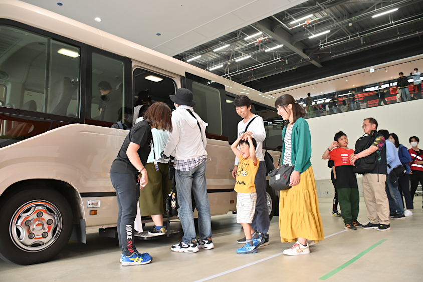バスに乗ってイベント広場に戻るROOKIE Racingキッズガレージツアーの参加者