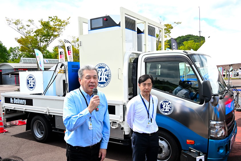 給水素トラックを説明するCJPT代表取締役社長の中嶋裕樹氏とJAF副会長の四宮慶太郎氏