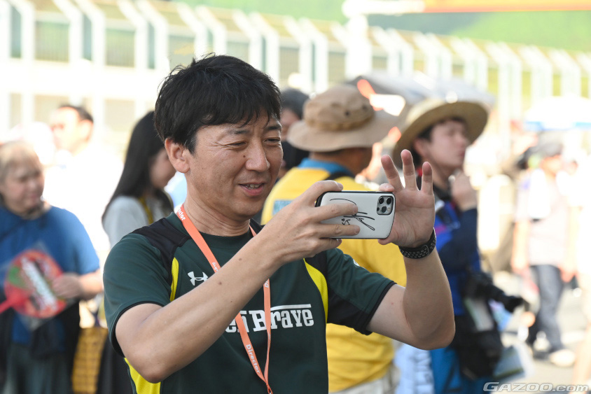 ファンとドライバーの写真を撮る青柳浩代表