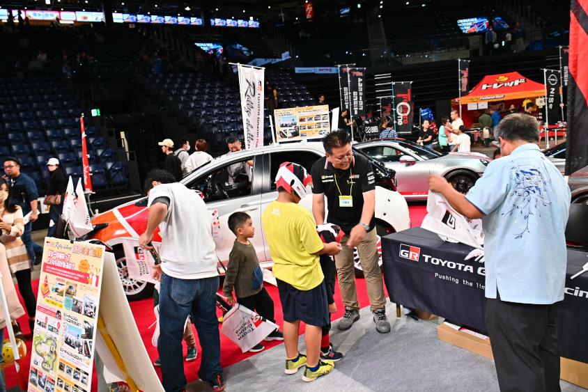沖縄トヨタ自動車のブースではノベルティの紙のヘルメットとフラッグを配布（オキナワモーターショー2023）
