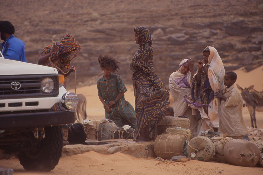 砂漠のオアシス近くの井戸で水を汲む人たち