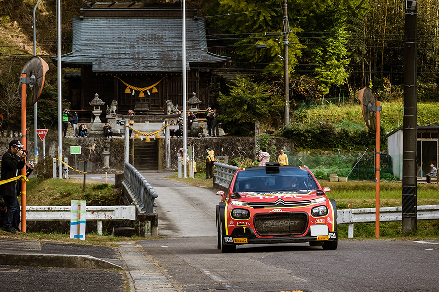 神社の前をラリーカーが駆ける。日本ならではの風景。
