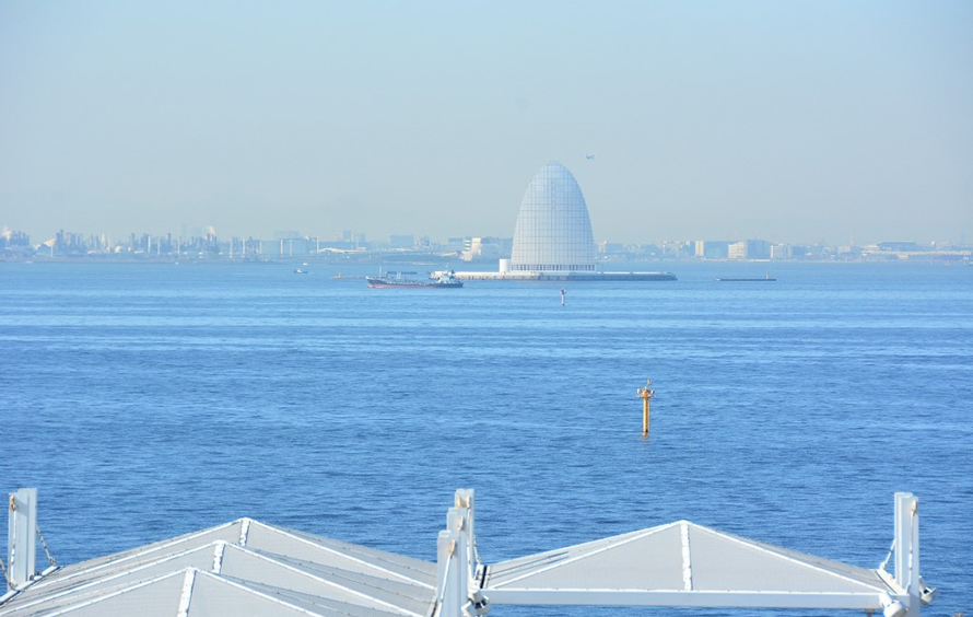 「海ほたる」から川崎側を眺めると海の中に白い三角の「風の塔」が見えます