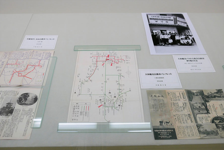 昭和初期の路線図、観光案内パンフレット、バス乗り場での社員の集合写真など。左が奈良自動車、右が大和観光自動車のもの。貴重な資料には個人所蔵のものも多い