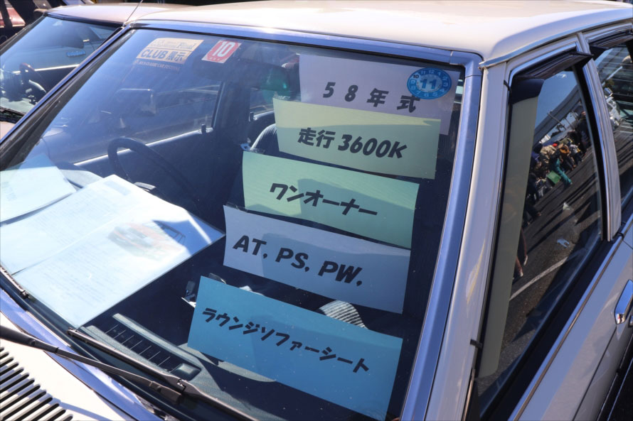 昭和58年式のマツダ・ファミリアは、当時の中古車店のような表示でクルマを解説。「ラウンジソファーシート」とは、後席の背もたれと側面の内装が連続して一体に見えるデザインのシート