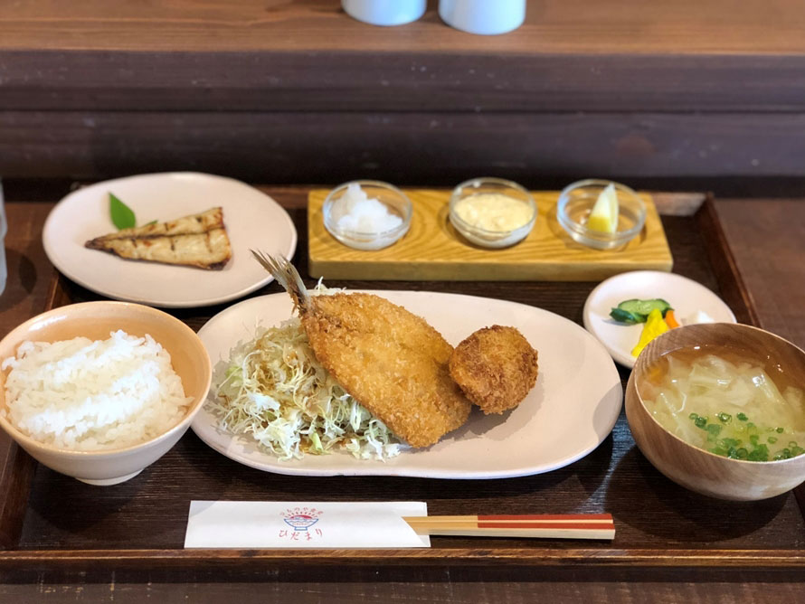 ランチタイムには「ひものや食堂ひだまり」の「あさひ（フライ定食）」1080円（税込）で、仙崎の味を堪能。サワラのメンチカツや肉厚のアジのフライに、目の前の漁港であがる新鮮なマサバの塩焼きが付いてボリューム満点。お米は油谷地区の棚田米を使っていて、おかわり自由なのがうれしい。